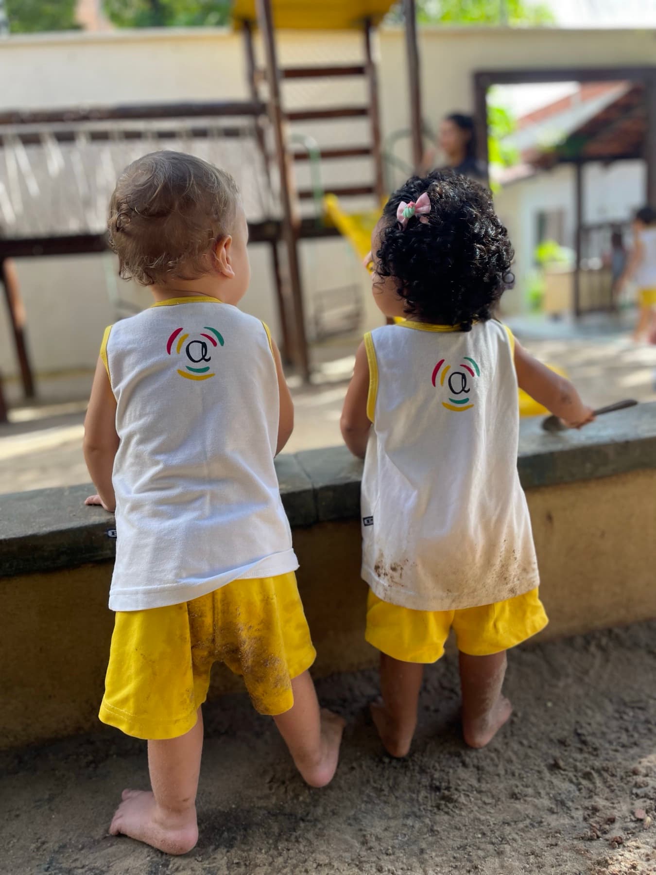 Dois bebês de uniforme observando o quintal do Ateliê Aquarela