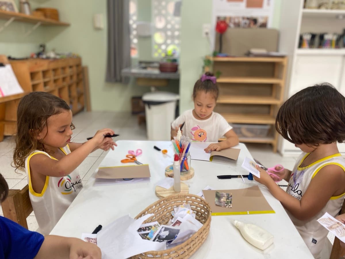 Crianças em mesa de atelier com materiais de arte