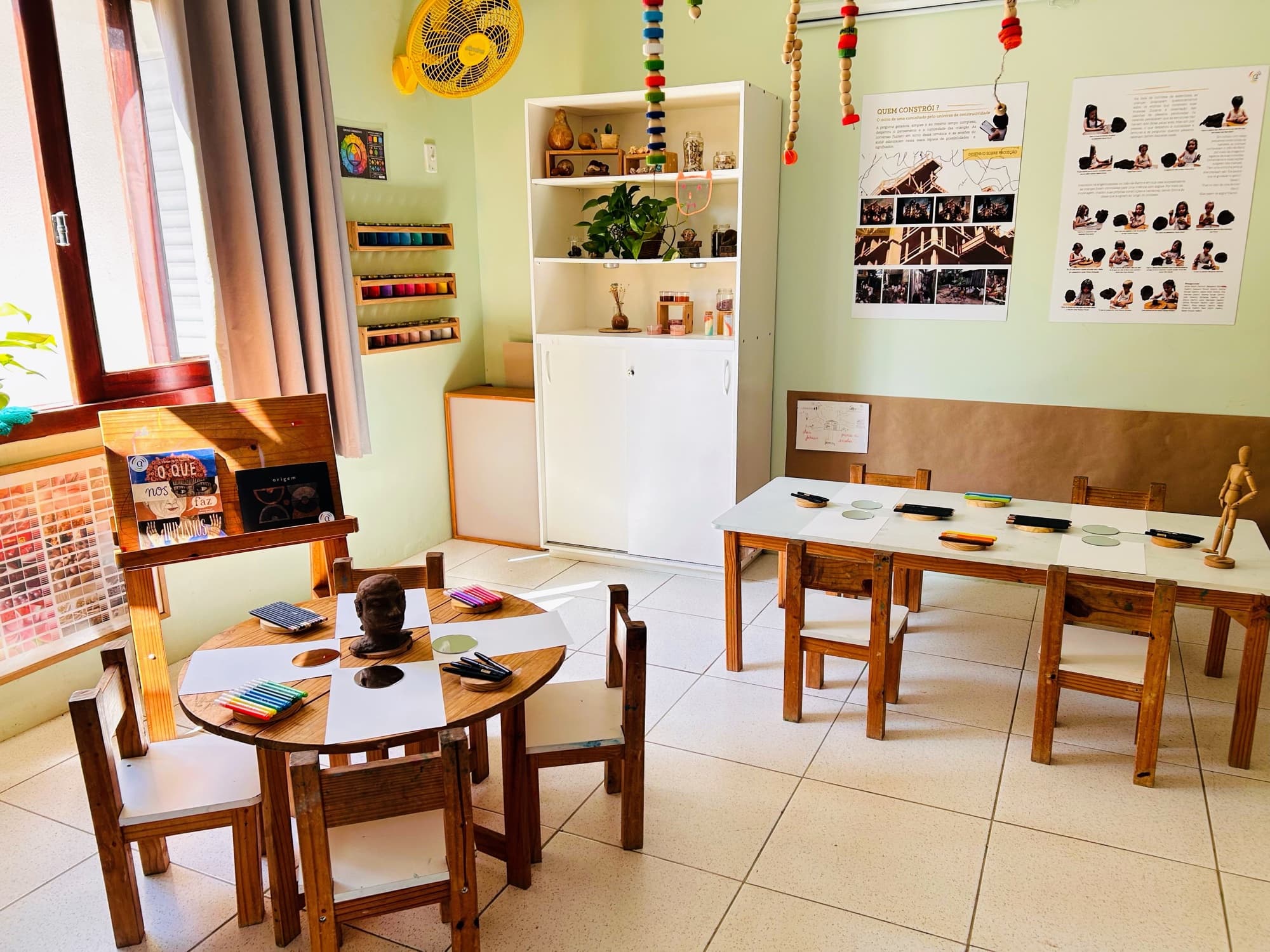 Sala de atelier organizada, com cavaletes e materiais à espera das crianças